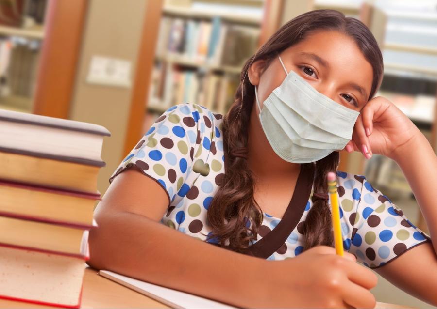 A pupil wearing a Covid mask, sitting by desk.