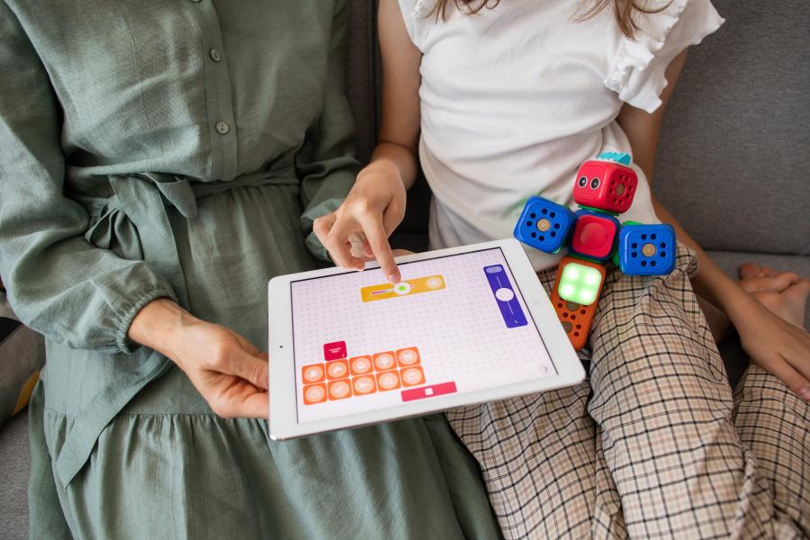 Child and adult playing on tablet