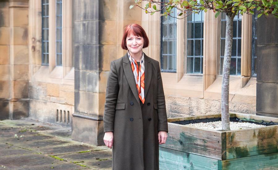Marian on the terrace, wearing a coat, smiling at the camera
