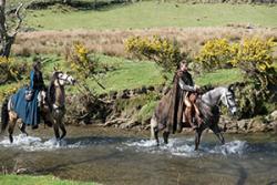 Riders on horses walking up a river from King Arthur: Legend of the Sword