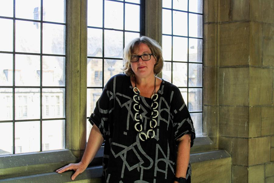 Gwenan Hine, wearing a black and grey top, standing by a window in Main Arts Building