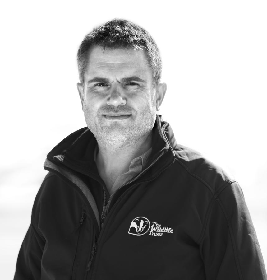 head and shoulder shot of a person in a fleece with a The Wildlife Trust logo