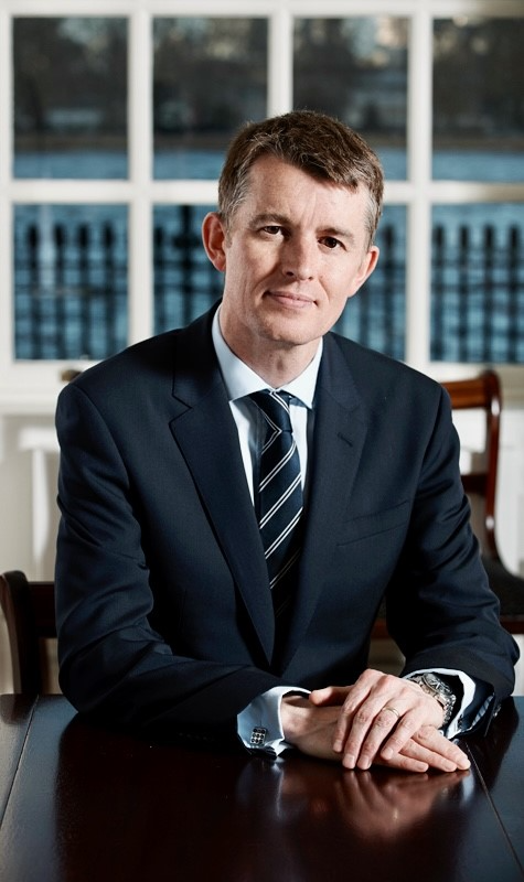 Person in a navy blue suit and tie sitting at a table