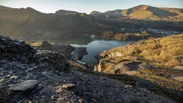 A landscape image of mountains with a sunrise in Wales