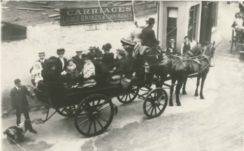 Photograph of a laden carriage taken outside a hire firm in Upper Bangor around the end of the 19th century.