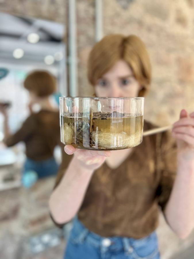 Artist holds bowl of materials suspended in water