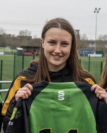 Portrait image of Kate holding up a rugby shirt