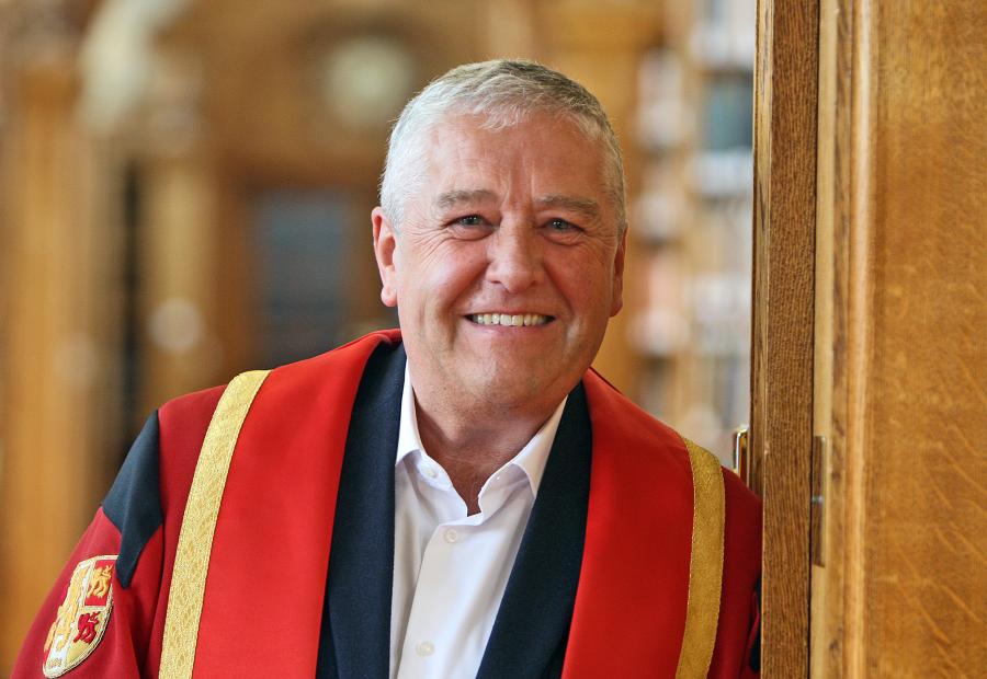 photograph of Mr Gwyn Evans in Bangor University library in graduation gown