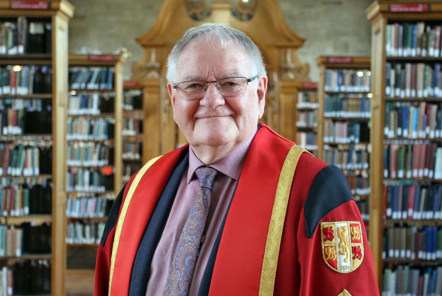 Photograph of Mr Dafydd Iwan in Bangor University library in graduation gown