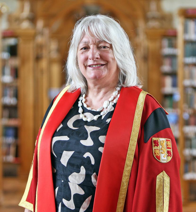 Photo of Dr Tina Barsby in Bangor University Library in graduation gown