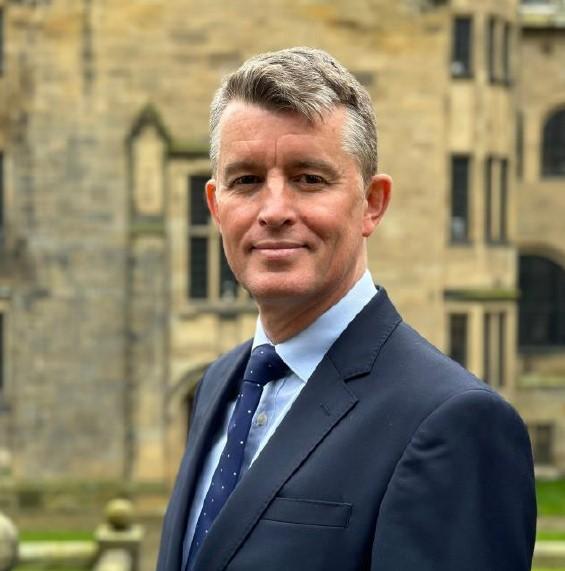 close-up photo of Mr Michael Flanagan in a business suit outside the Main University Building