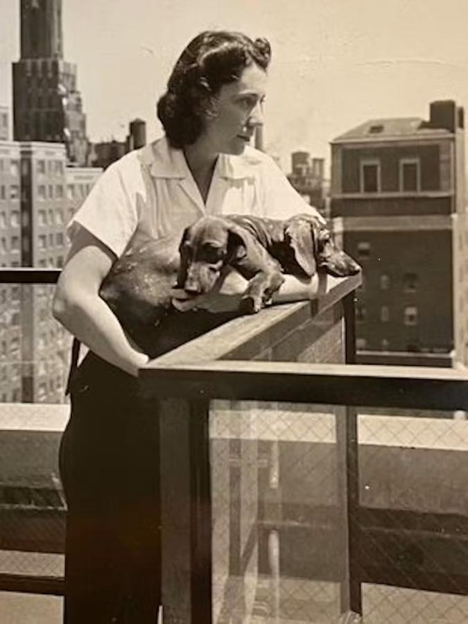 black and white image of woman looking out from balcony