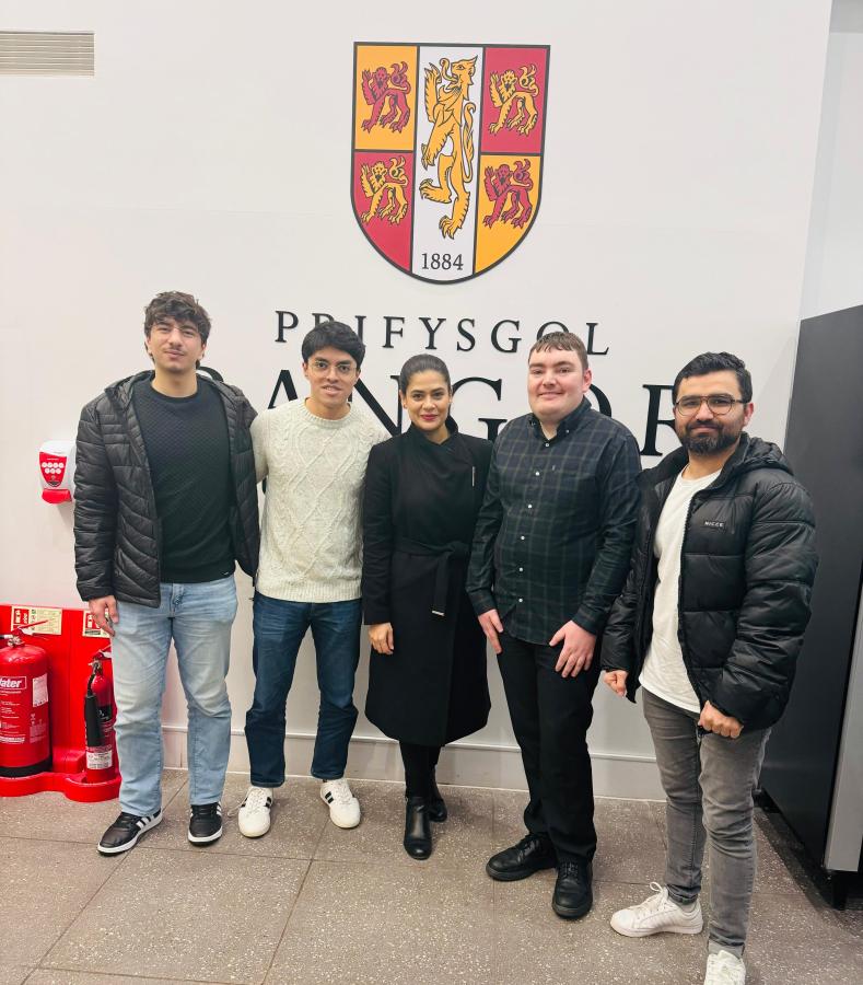 Students standing in front of Bangor University crest