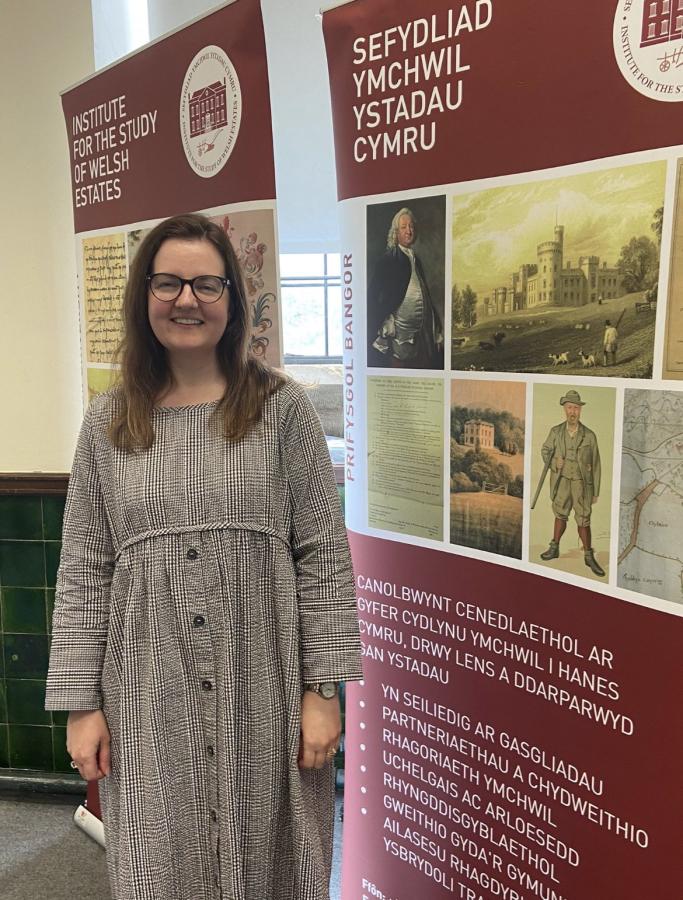 Dr Lowri Ann Rees stands in front of an Institute for the Study of Welsh Estates banner
