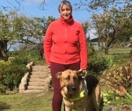 A woman and guidedog standing by trees