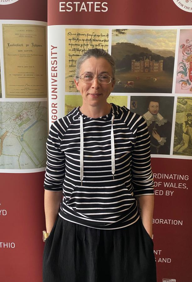 Doctoral Researcher Lizzy stands in front of an ISWE banner.