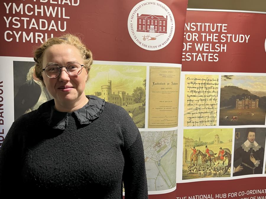 A photograph of doctoral student Daisy Hughes standing in front of the ISWE banner