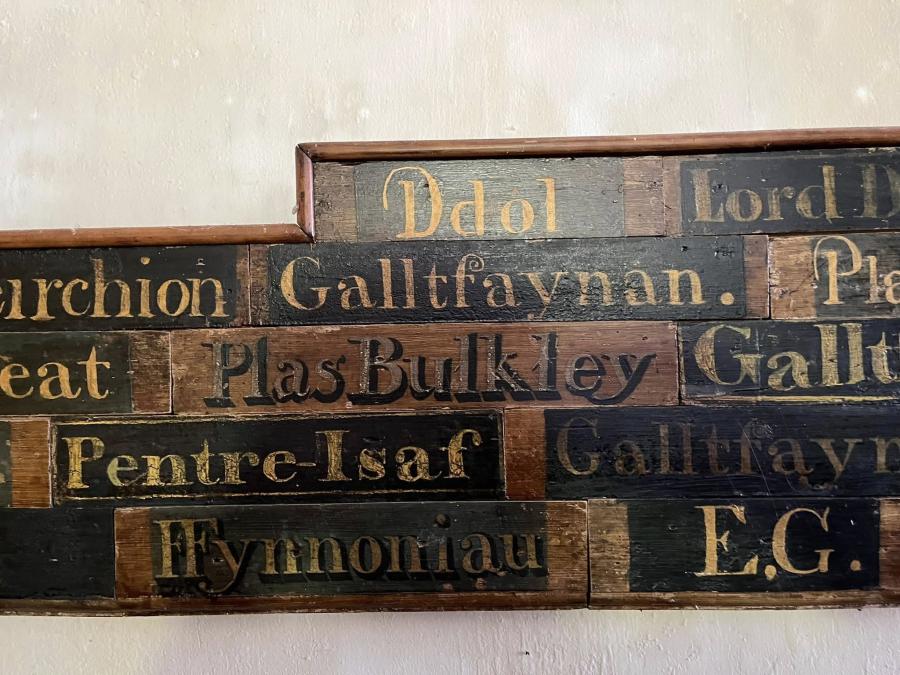 Cyfres o blatiau enw mewn gwahanol ffontiau, gan gynnwys Ddol, Galltfaynan, Plas Bulkley, Pentre-Isaf