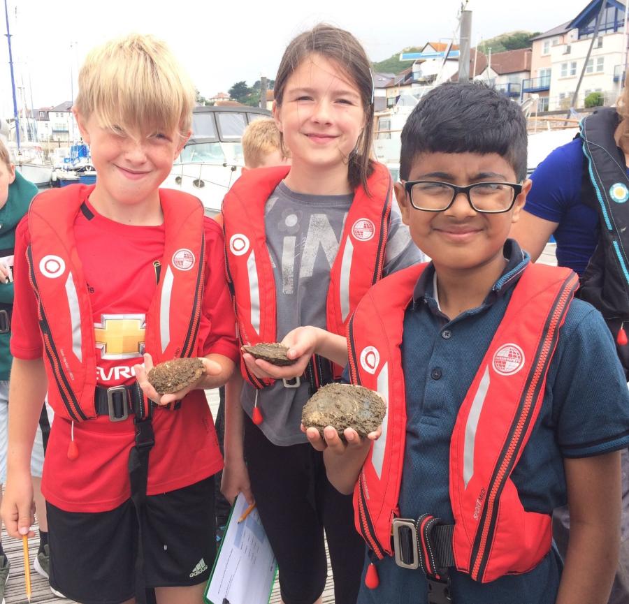 Three children holding native oysters at Conwy Marina
