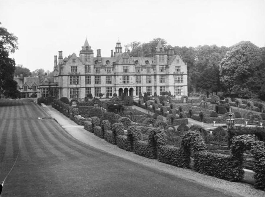 Black and white photograph of a Neo-Jacobean house with hedges in the foreground