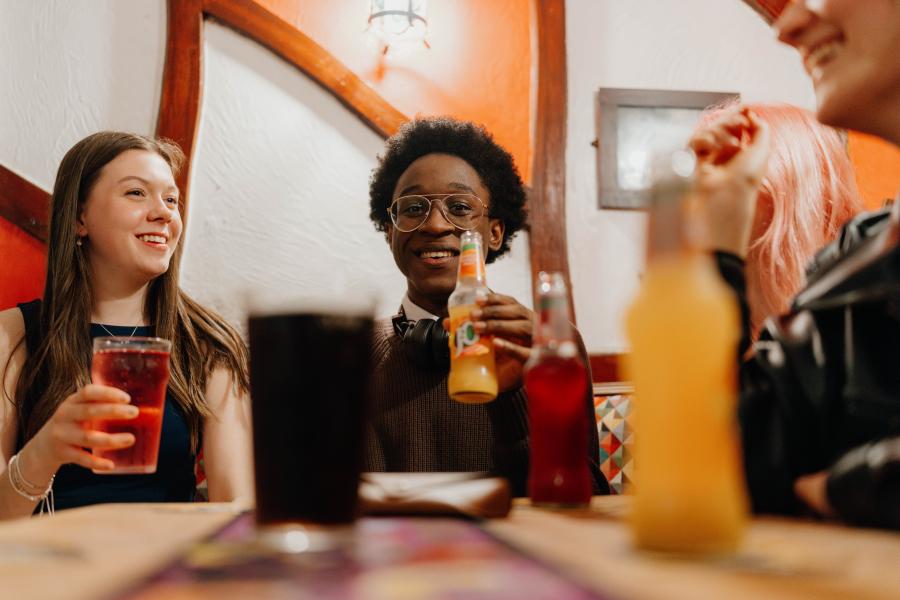 A group of students in a pub setting at a table, socialising and drinking soft drinks.