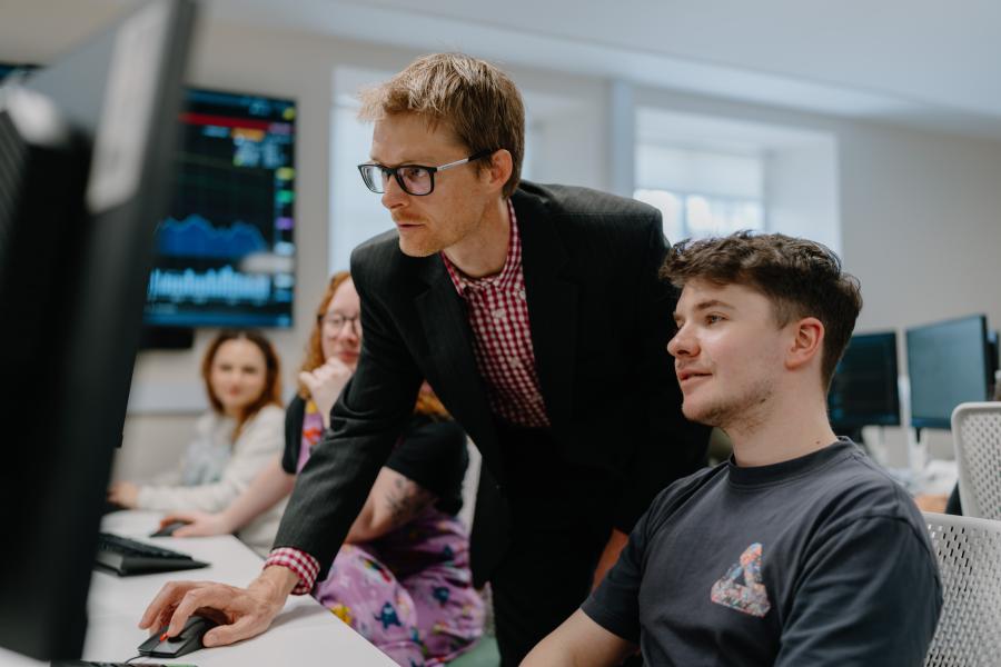 A students with a lecturer looking at the Bloomberg terminals in the University trading floor 