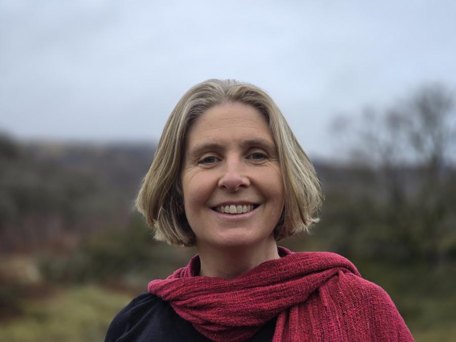 An image of Professor Julia Jones. She has short blonde hair and is standing outdoors wearing a black top and a textured red scarf.
